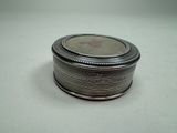 a small silver box with a silver lid on a white surface
