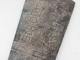 un vieil objet en pierre portant une inscription, posé sur une surface blanche
