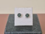 a pair of emerald earrings on a marble block