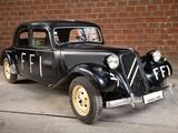 a black car that is parked in front of a brick wall