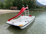 a white boat with a red slide in the water