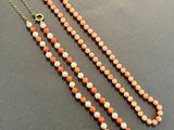 an orange and white beaded necklace with a gold clasp