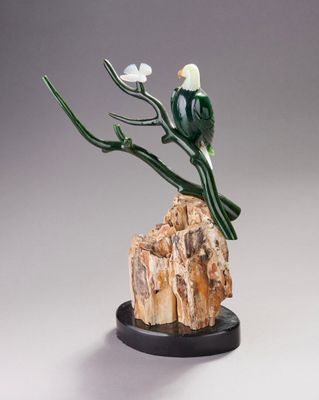 sculpture représentant un oiseau perché sur une branche d'arbre posée sur un rocher