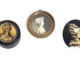 three framed portraits of women and men are displayed on a white surface