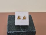 a pair of gold triangle stud earrings sitting on top of a marble block