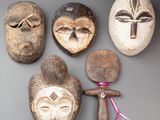 Plusieurs masques africains sont accrochés au mur d'une pièce.