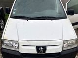 La petite camionnette blanche est garée sur un parking, à côté d'autres voitures.