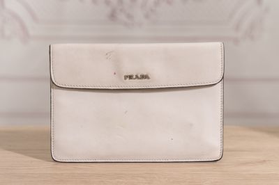 a white purse sitting on top of a wooden table next to a wall