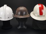 three hard hats on a mannequin head on a black background