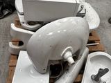 une pile de cuvettes de WC et un lavabo posés sur une palette