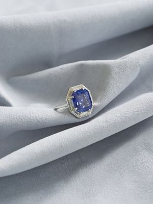 un gros plan d'une bague ornée d'un saphir bleu posée sur un tissu blanc