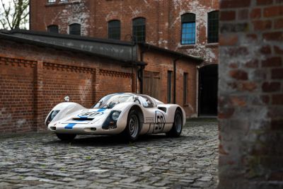 a white and blue race car parked in front of a brick building