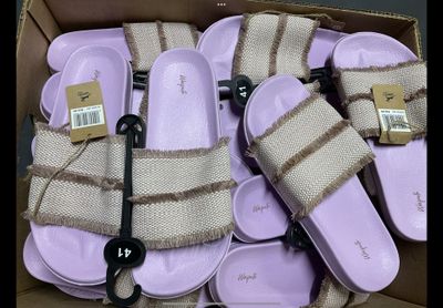 de nombreuses paires de sandales dans une boîte posée par terre