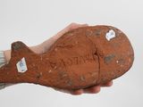 a person holding a piece of clay with writing on it