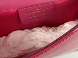 someone is holding a pink purse with a white shirt underneath it