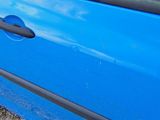 a close up of a blue car door with a hole in it
