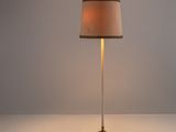 le lampadaire est posé sur une surface blanche et est muni d'un abat-jour beige