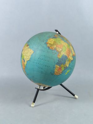 un globe bleu et vert posé sur un socle en bois