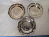four silver plates sitting on top of a table next to each other