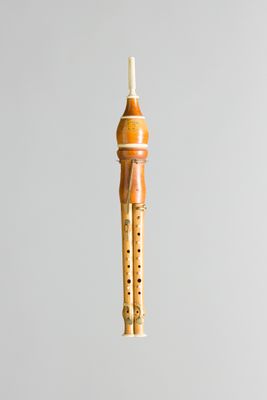someone is holding a wooden flute in their hand on a gray background