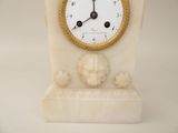 a white clock with a gold frame on a marble stand