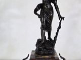 une statue représentant une femme tenant un oiseau et une horloge