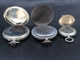 three silver pocket watches sitting next to each other on a table