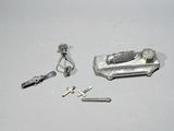 une petite boîte en argent contenant une clé, une bague et d'autres objets, posée sur une surface blanche