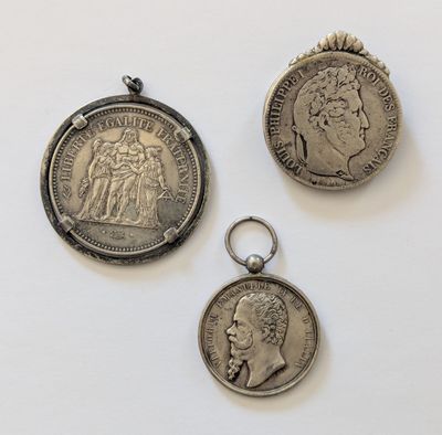 trois pièces d'argent et un porte-clés en argent posés sur une surface blanche