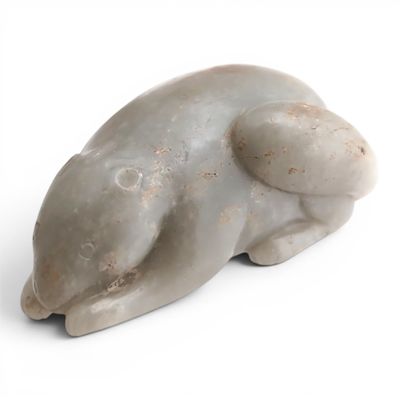 une petite statue représentant un ours posée sur une surface blanche