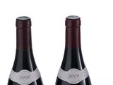 four bottles of wine are lined up in a row on a white surface