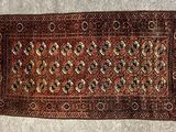 Un vieux tapis est posé par terre près d'un mur.