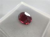 a close up of a red diamond sitting on top of a white surface