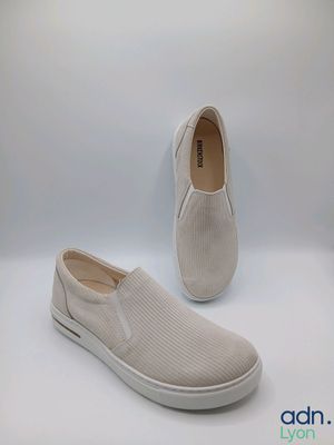 a pair of white slip on shoes on a white background