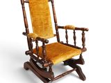 an old rocking chair with a yellow upholstered seat on a white background