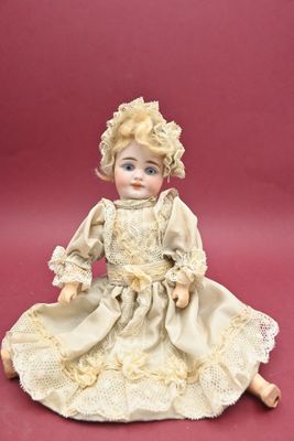 une poupée assise par terre sur un fond rose