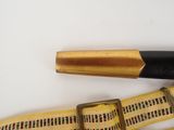 a black and gold pen and a yellow strap