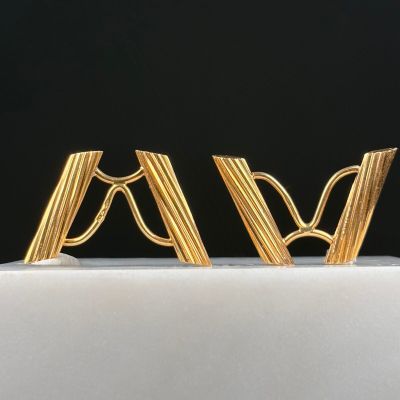 two gold earrings are sitting on top of a white cake