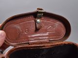 a person holding a leather case with a ring inside of it