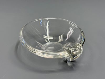 a clear glass bowl with a metal handle on a table