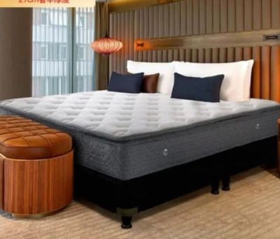 a bed with a mattress and a foot stool in a room