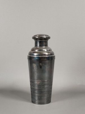 un shaker à cocktail argenté posé sur une surface blanche