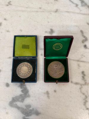 deux médailles d'argent et d'or dans une boîte verte posée sur un socle en marbre