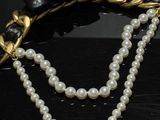 pearl and gold necklace with a bow on a black surface
