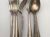 three forks and a spoon are sitting on a white surface
