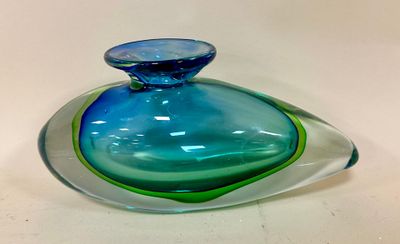 a blue and green glass vase on a white table