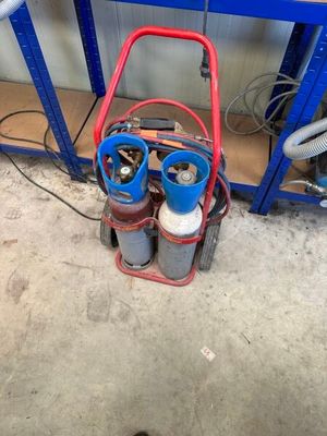 a red cart with two gas bottles on it in a garage