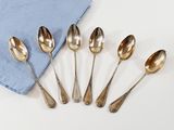six silver spoons and a blue napkin on a white surface