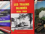 trois livres sur une étagère, avec un train en arrière-plan