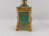 a small gold and green bottle with a clock on it